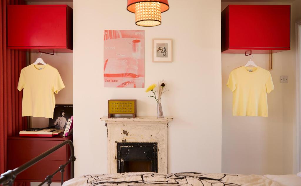 sypialnia z czerwonymi szafkami i kominkiem z 2 koszulami w obiekcie Modja Modja House w mieście Kent