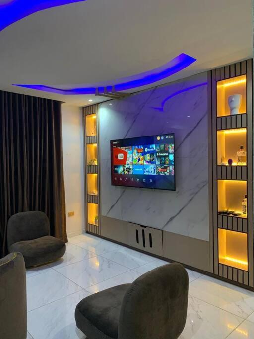 a room with two chairs and a flat screen tv at Loft and Luxe Apartment in Lagos