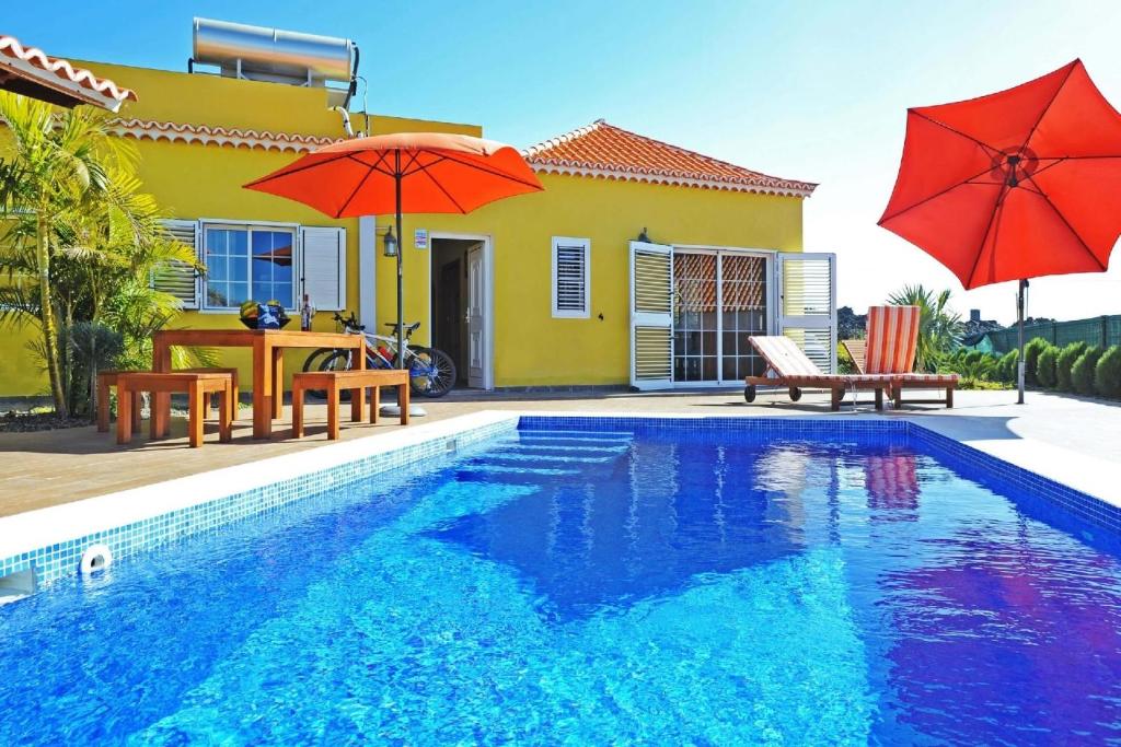 a pool with two red umbrellas and a house at Ferienhaus mit Privatpool für 6 Personen ca 108 qm in Las Manchas, La Palma Westküste von La Palma in Puerto Naos