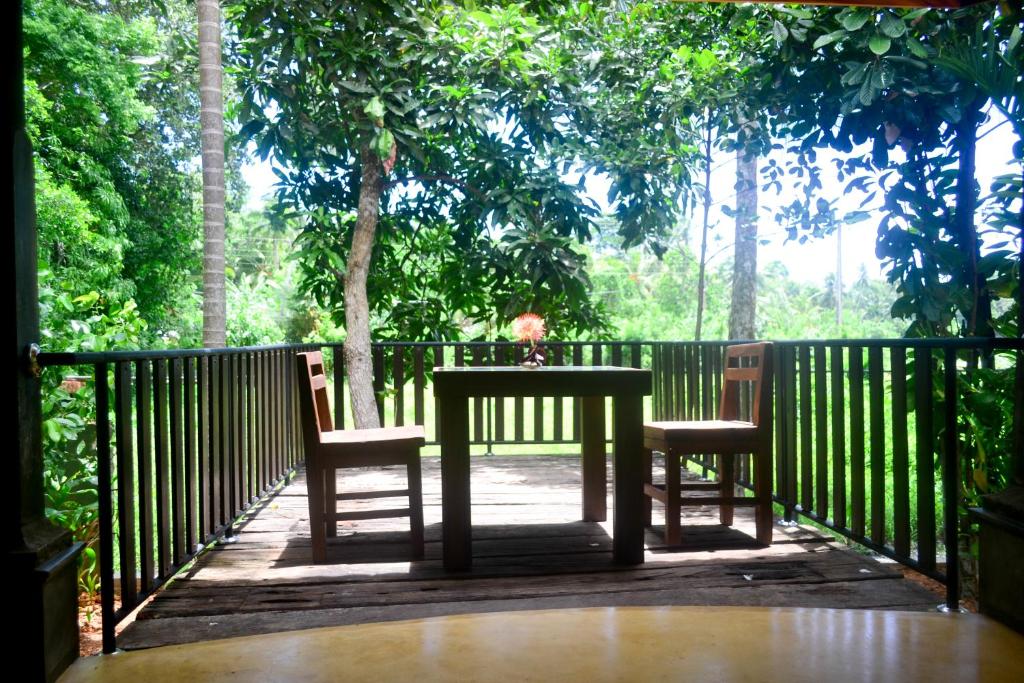 a table and two chairs on a wooden deck at Guruwaththa Eco Lodge in Hikkaduwa
