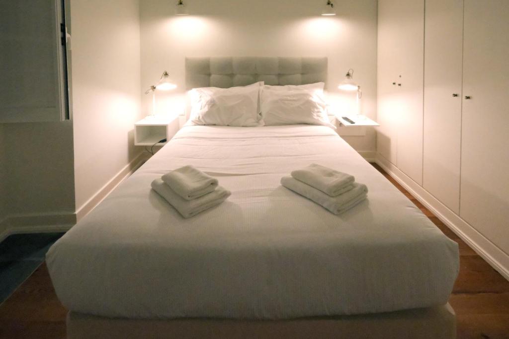 a bedroom with a large white bed with two towels on it at Apartamentos Ázera - António Ázera in Praia da Vitória