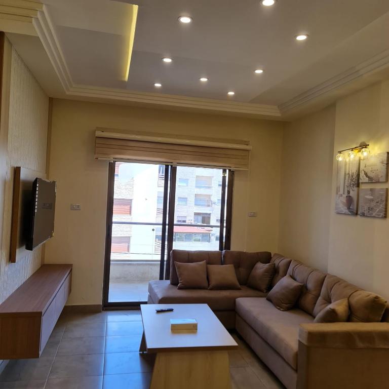 uma sala de estar com um sofá e uma televisão em 24th Apartment em Amã