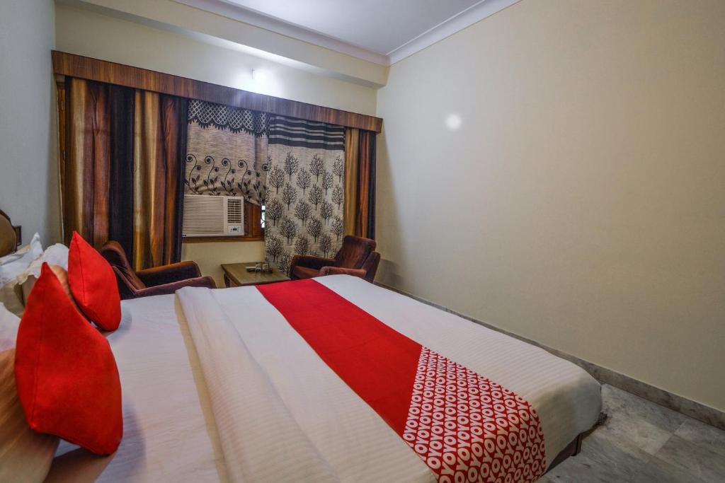 a bedroom with a bed with red pillows and a window at Hotel Vinayak in Udaipur