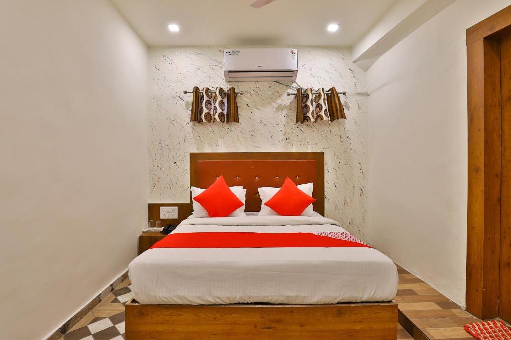 a bedroom with a large bed with red pillows at OYO Hotel Surya in Ahmedabad