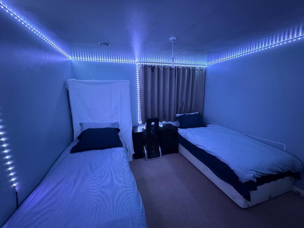 two beds in a room with blue lights at London gateway get-away in Hounslow