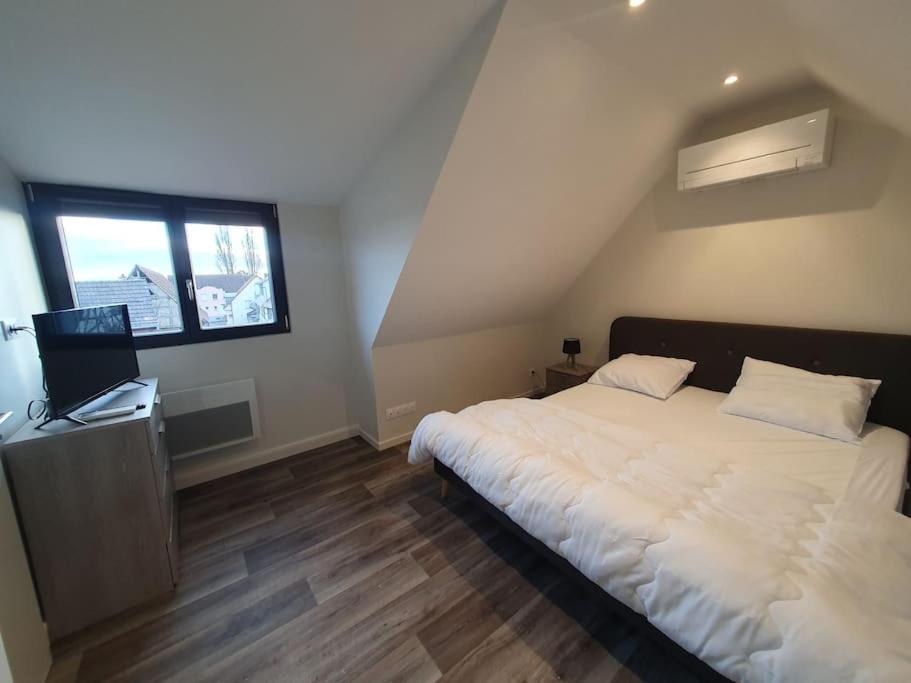 een slaapkamer met een groot wit bed en een raam bij Appartement 2 pièces tout confort, aux portes de Colmar in Andolsheim