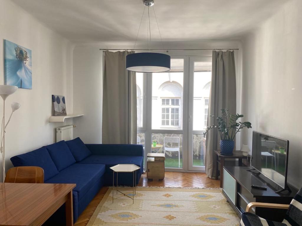 ein Wohnzimmer mit einem blauen Sofa und einem großen Fenster in der Unterkunft Wisła River Apartment in Warschau