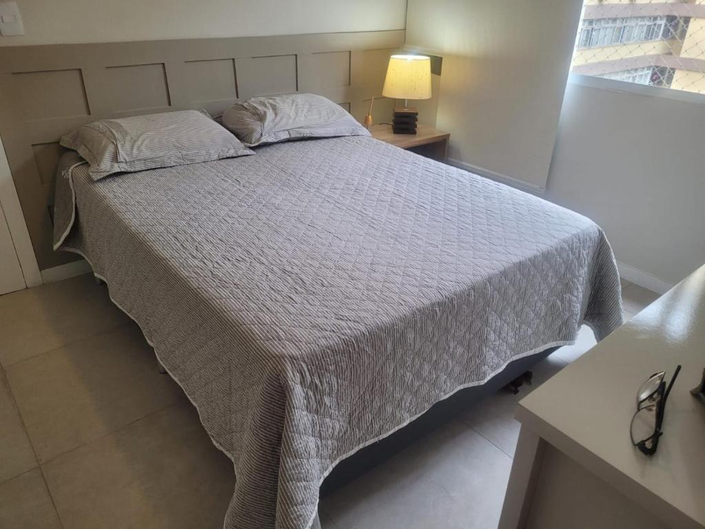 um quarto com uma cama com um edredão branco em Apartamento em Ipanema no Rio de Janeiro