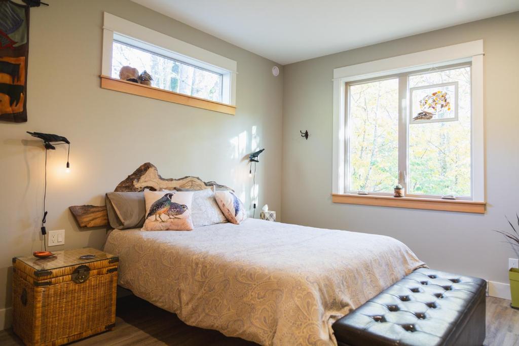 um quarto com uma cama grande e 2 janelas em Cowichan Valley Guest Cottage em Ladysmith