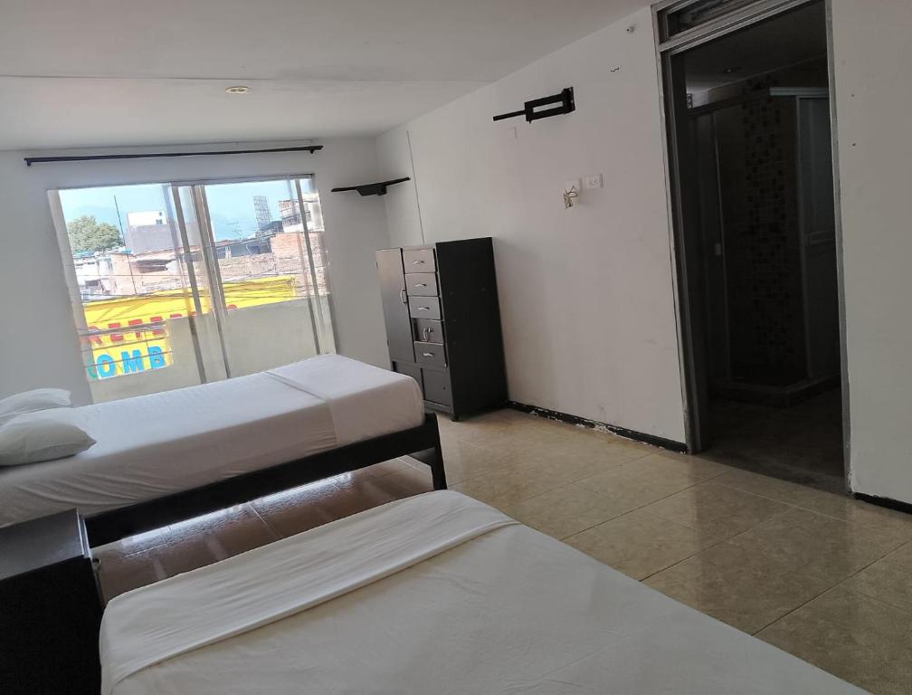 sypialnia z 2 łóżkami i oknem w obiekcie Hotel Bolivariano AV w mieście Ibagué