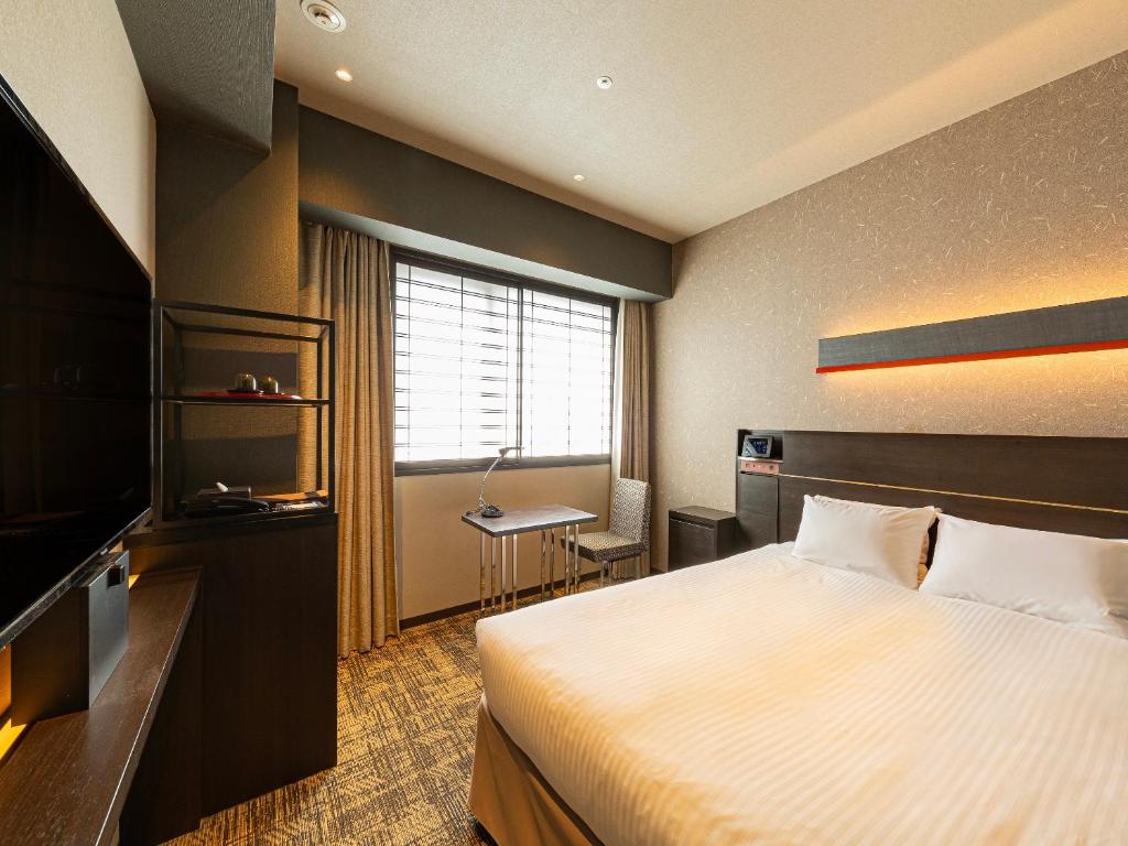 Pokój hotelowy z łóżkiem i biurkiem w obiekcie Hotel Keihan Kyoto Hachijoguchi w mieście Kioto