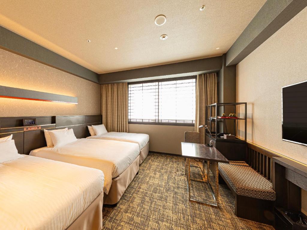 a hotel room with two beds and a flat screen tv at Hotel Keihan Kyoto Hachijoguchi in Kyoto