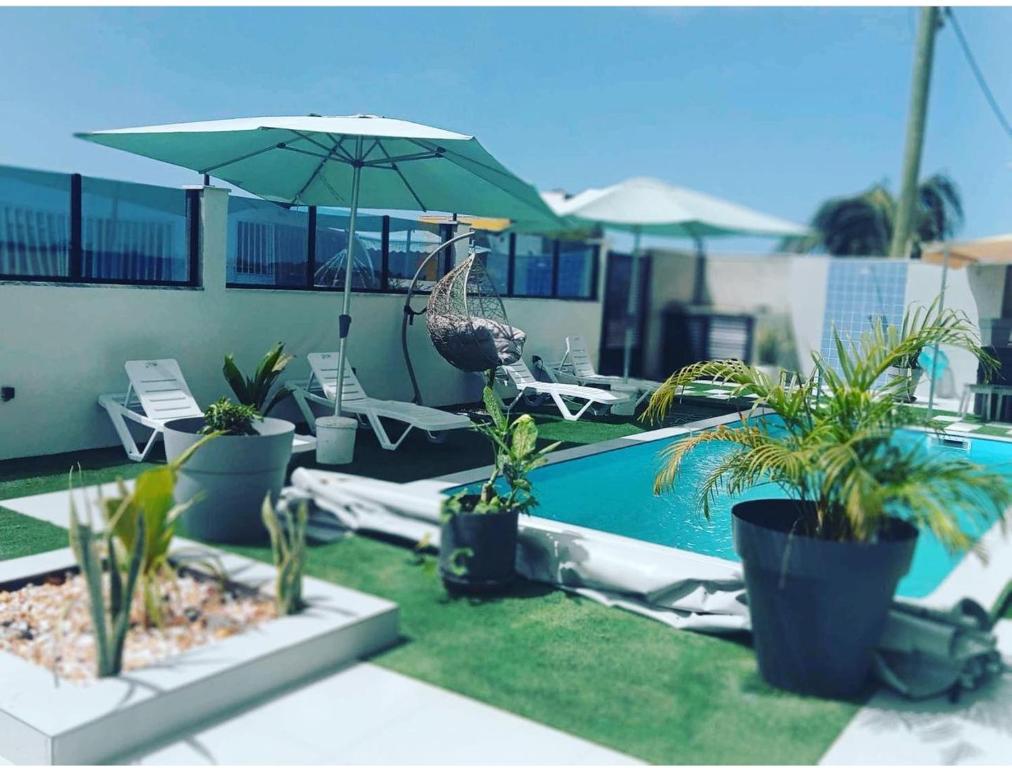 - une piscine avec des chaises, un parasol et des plantes dans l'établissement Hotel Xinte na casa, à Tarrafal