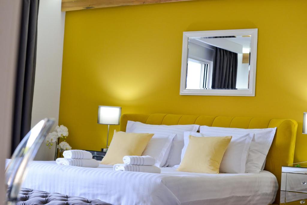 a bedroom with a large bed with a yellow wall at PIAZZA ROOMS Zadar in Zadar