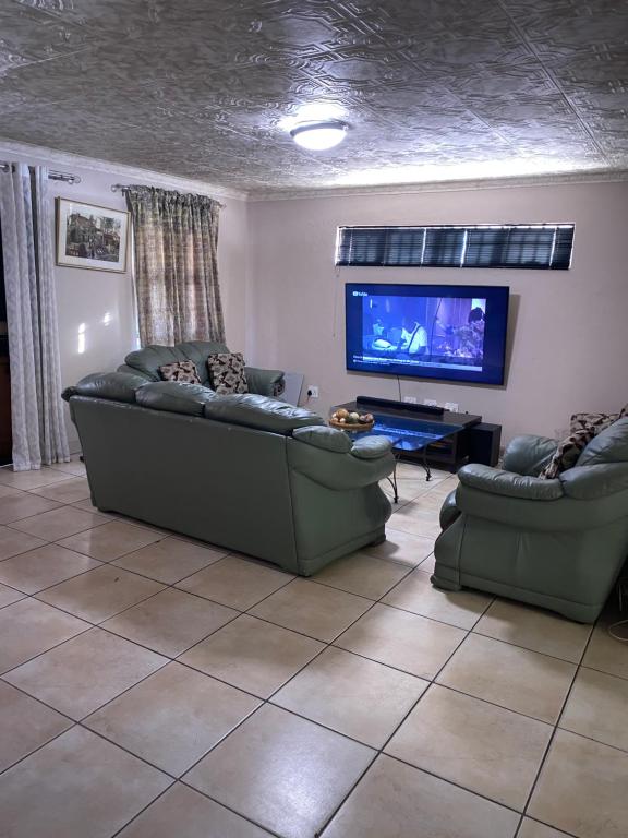 a living room with couches and a flat screen tv at Ludinz Guest House & Self catering in Cape Town