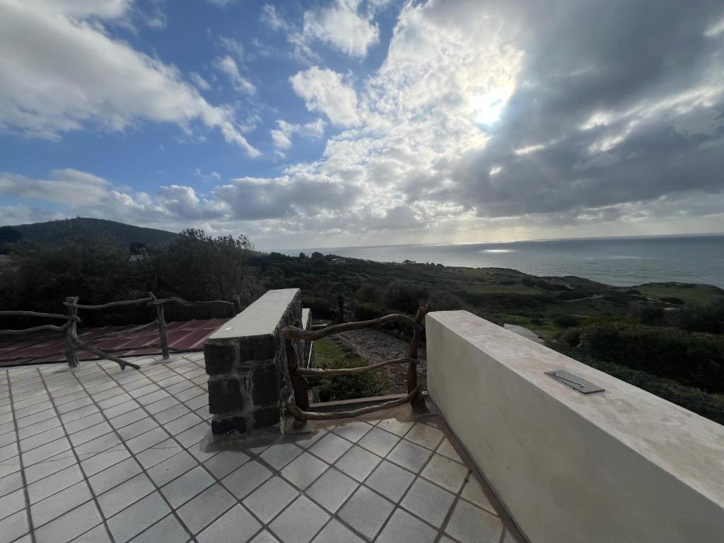 uma vista para o oceano a partir de um edifício com um banco em Villa del sole em Magomadas
