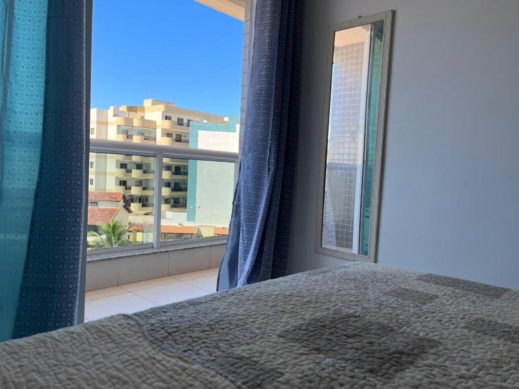 um quarto com uma cama e uma grande janela em Apartamento Por do sol Le Bon Vivant em Arraial do Cabo
