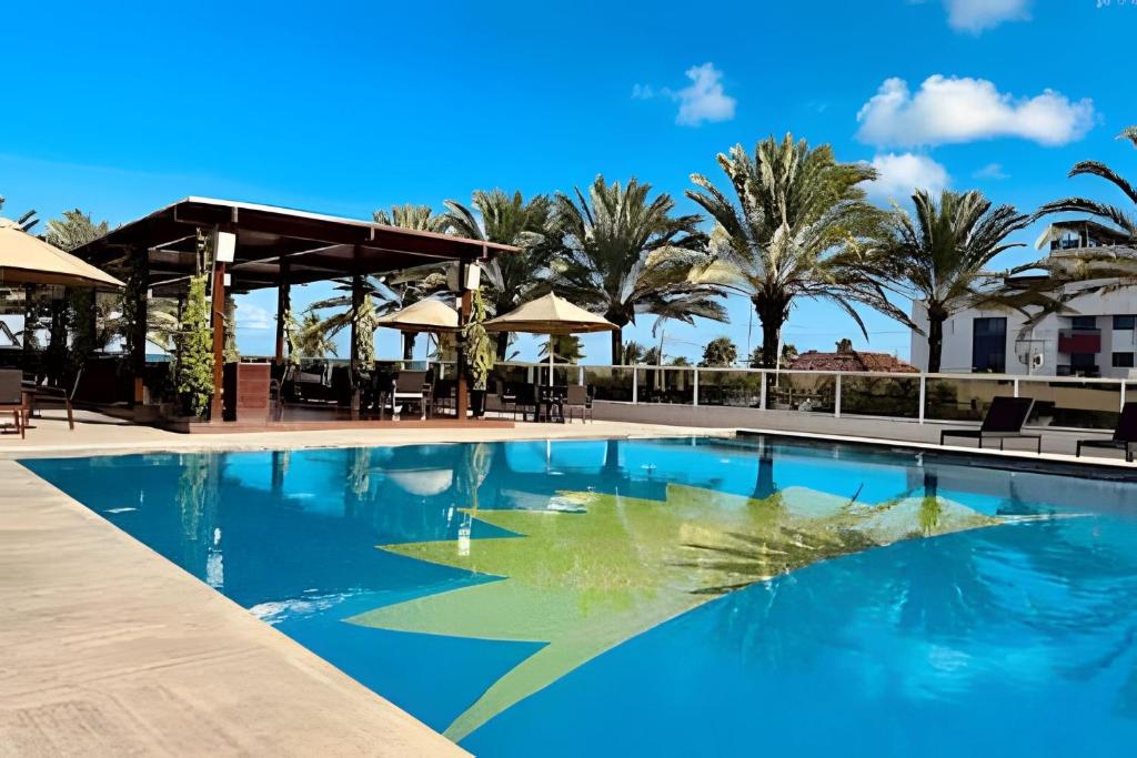 uma piscina num resort com palmeiras em Apto Luxo 2 quartos no Solar Tambaú em João Pessoa