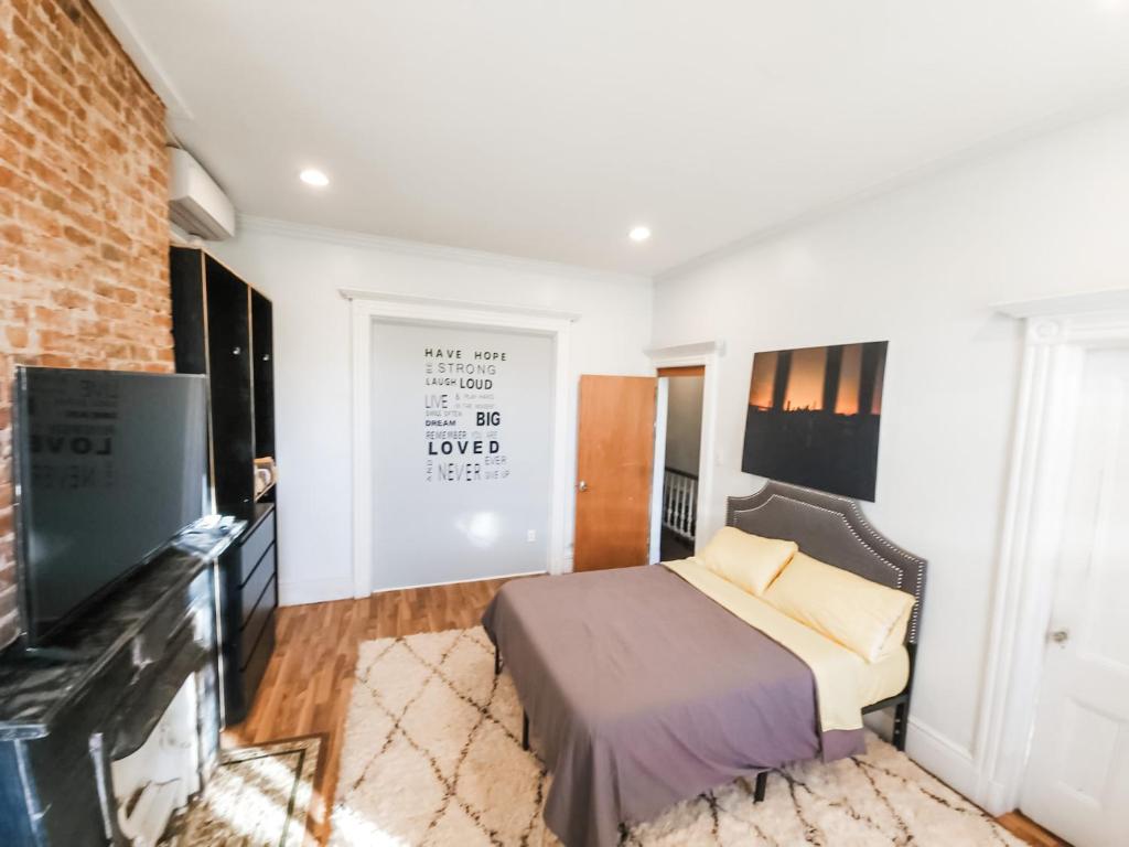 1 dormitorio con 1 cama y TV de pantalla plana en Historic Bushwick, Brooklyn Brownstone Apartment, en Brooklyn