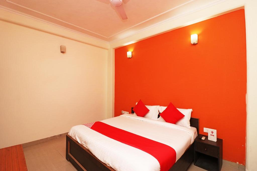 a bedroom with a bed with an orange wall at OYO Hotel Grand Casa Near Aravali Biodiversity Park in Gurgaon