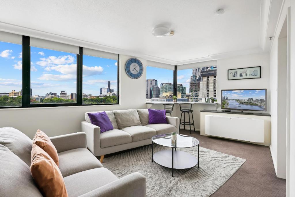 a living room with two couches and a table at 1-Bed Brisbane City Pad with Sweeping Views in Brisbane