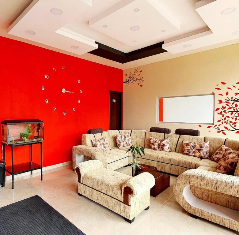 - un salon avec des canapés et un mur rouge dans l'établissement Hostal La Cocha, à Latacunga