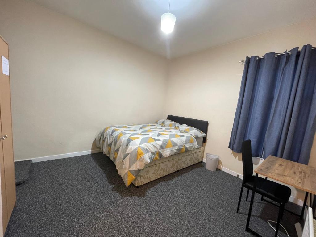 a bedroom with a bed and a table and blue curtains at Private double rooms near City centre, Coventry with free Parking/WiFi in Coventry