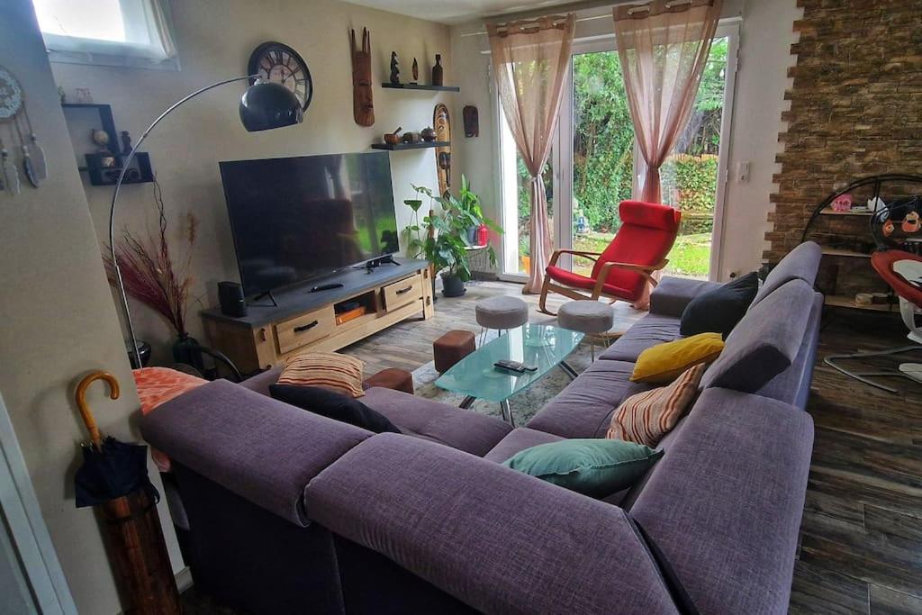 GagnyにあるMaison avec jardin 25mn de parisのリビングルーム(紫色のソファ、テレビ付)