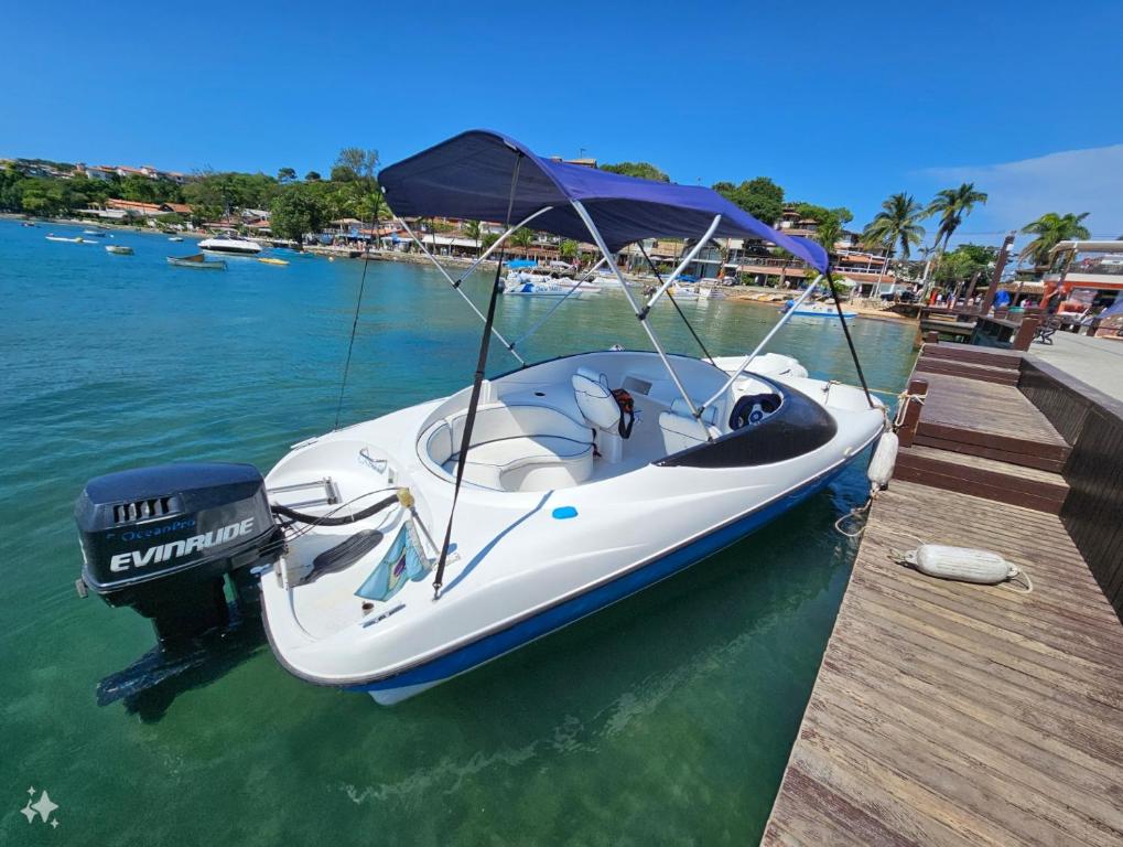 a white boat parked next to a dock in the water at CALU III in Búzios