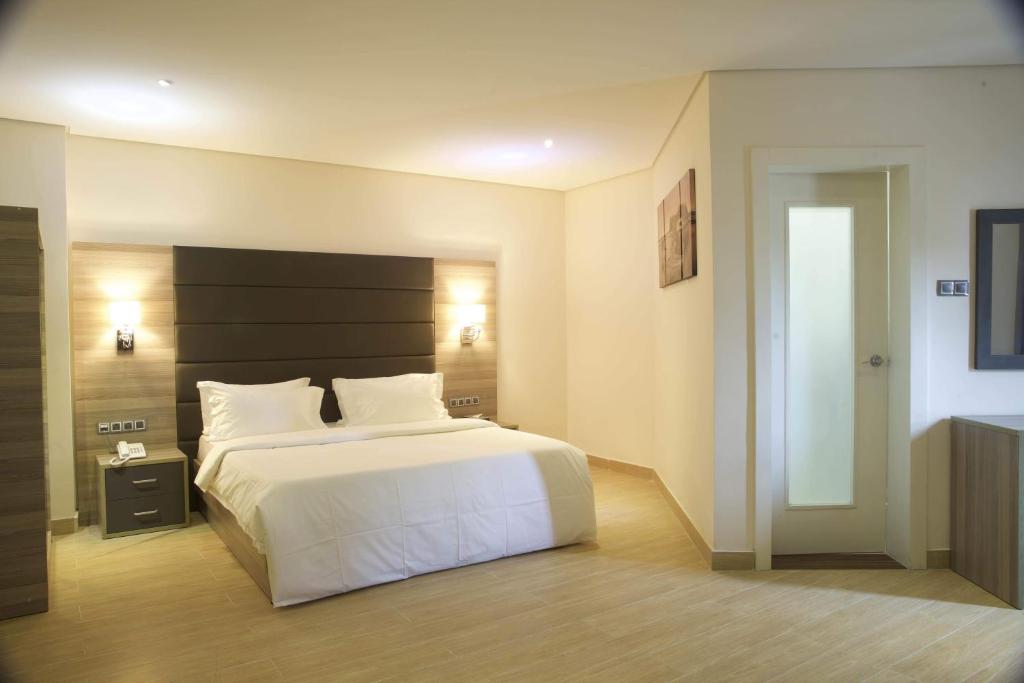 - une chambre avec un lit blanc et une tête de lit noire dans l'établissement Scarlet Lodge, à Lagos