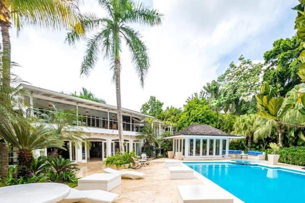 an exterior view of a resort with a swimming pool and palm trees at Villa Beach & Golf CASA DE CAMPO in La Romana