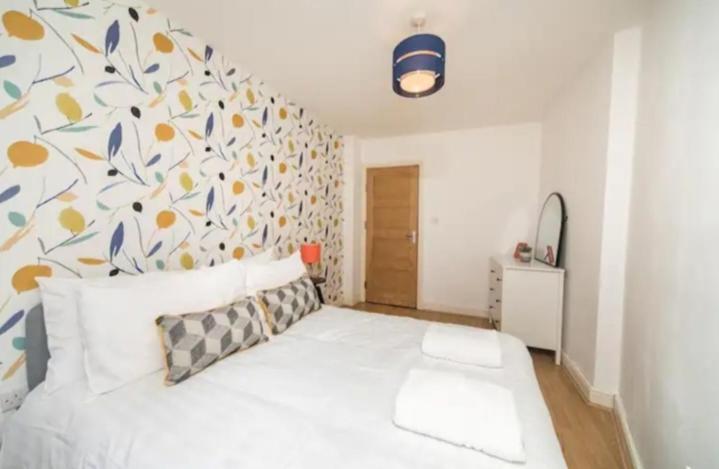 a bedroom with a white bed with a floral wall at Spacious one bedroom apartment in Reading
