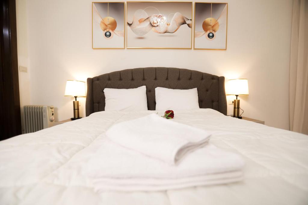 a white bed in a bedroom with two lamps at Duplex-Nyoum New Cairo in Cairo