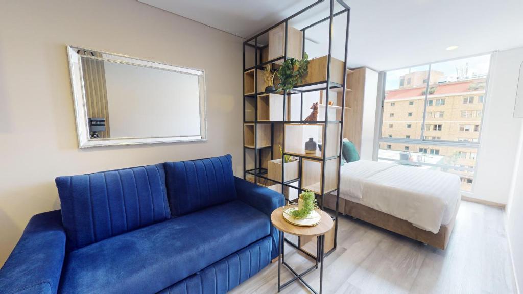 uma sala de estar com um sofá azul e uma cama em Your Home in the Heart of Bogotá em Bogotá