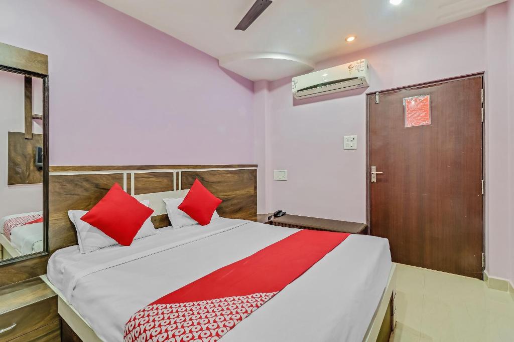 um quarto com uma cama grande e almofadas vermelhas em Hotel Royal em Rāj Nāndgaon