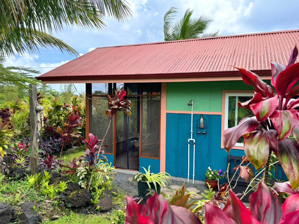 Pahoa的住宿－Tropical Zen Bungalow，绿色和蓝色的房子,有红色屋顶