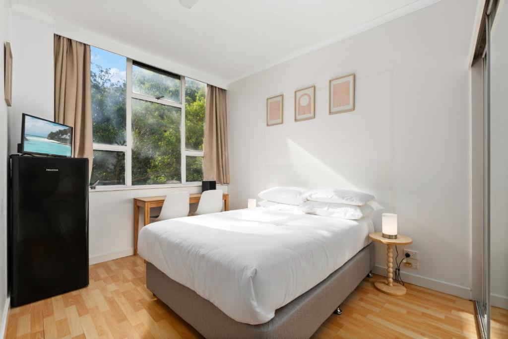 ein weißes Schlafzimmer mit einem großen Bett und einem Fenster in der Unterkunft Perfectly Located Studio by Rushcutters Bay Park in Sydney