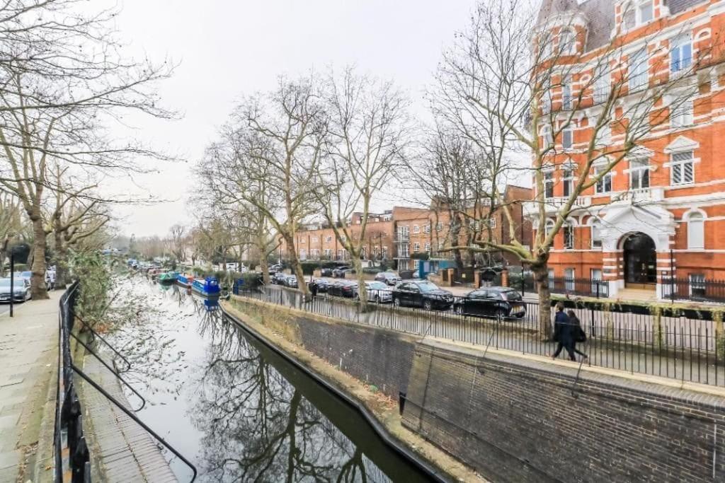 a person walking down a street next to a river at Little Venice Maisonette in London