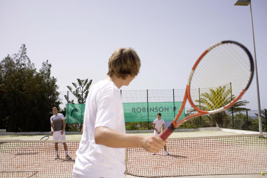 a man holding a tennis racket on a tennis court at ROBINSON ESQUINZO PLAYA - All Inclusive in Morro del Jable