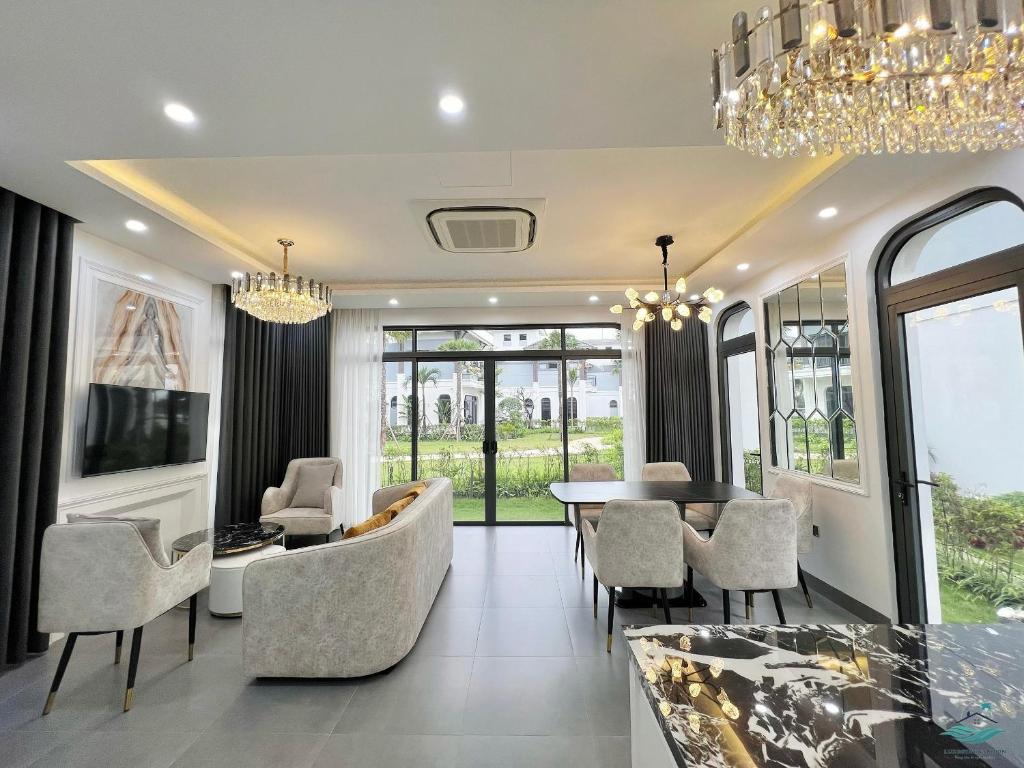 uma sala de estar com um lustre e uma mesa e cadeiras em Royal Beach Villa Sonasea Vân Đồn Quảng Ninh 