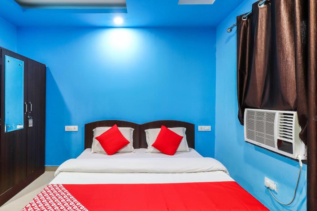 - un lit avec des oreillers rouges dans une chambre bleue dans l'établissement OYO Flagship 62748 Hotel Zeenat, à Jammu