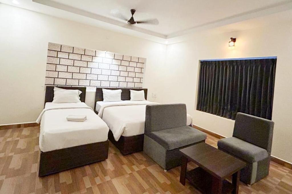 1 dormitorio con 2 camas, silla y ventana en R Hotels By Suraj Residency Yercaud, en Yercaud