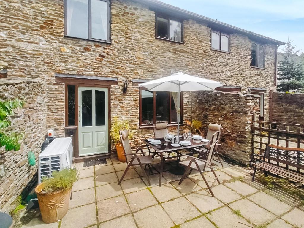 a patio with an umbrella and a table and chairs at The Popples in Ivybridge