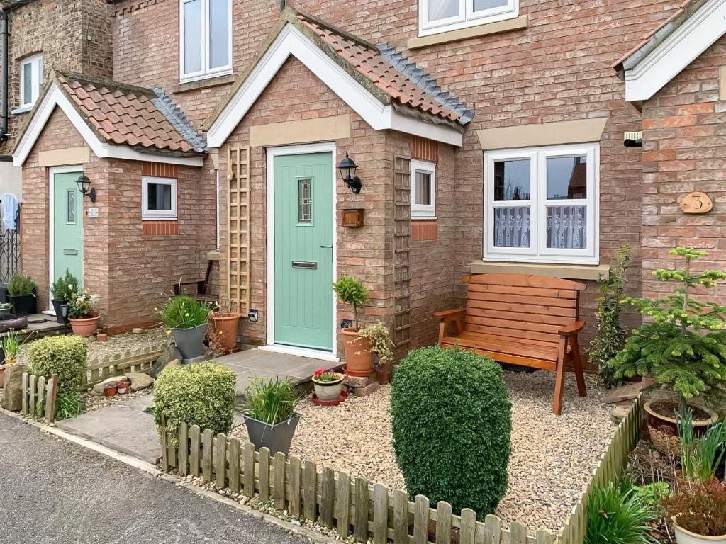 a house with a green door and a bench at Middle Cottage in Thirsk