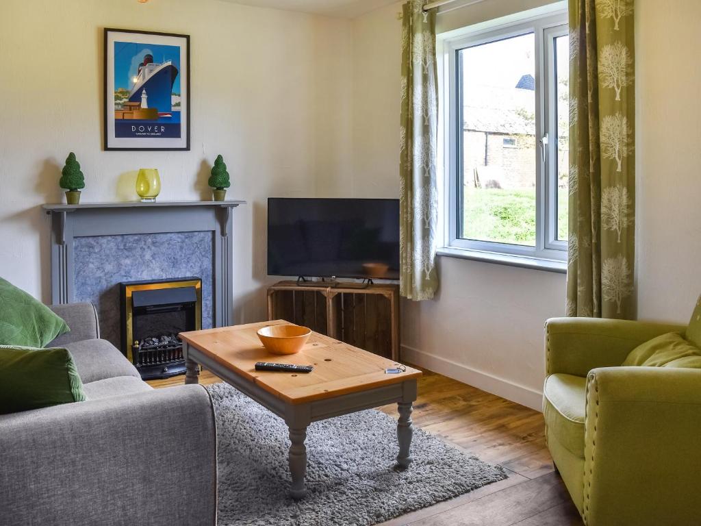a living room with a fireplace and a tv at The Hayloft - Uk46186 in St Margarets at Cliff