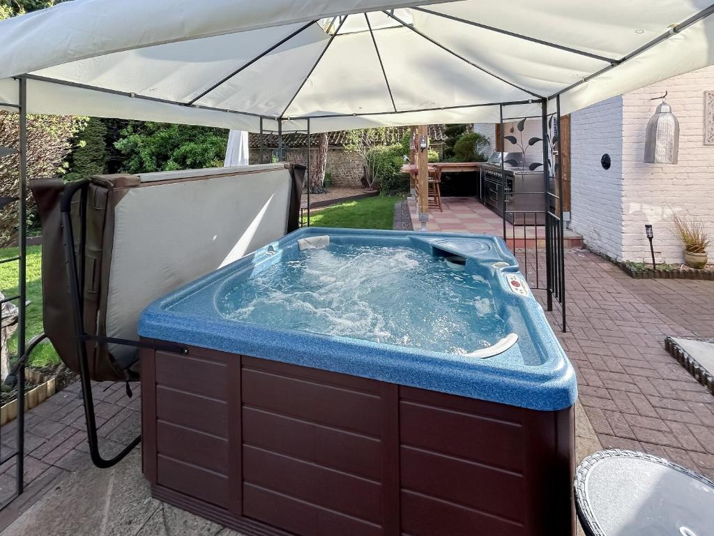 uma banheira de hidromassagem sob um guarda-sol num pátio em Moulsham House em Stoke Ferry