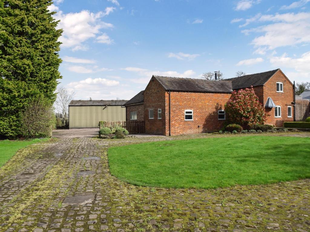 an old brick house with a grass yard at Brook Farm Cottage in Nantwich