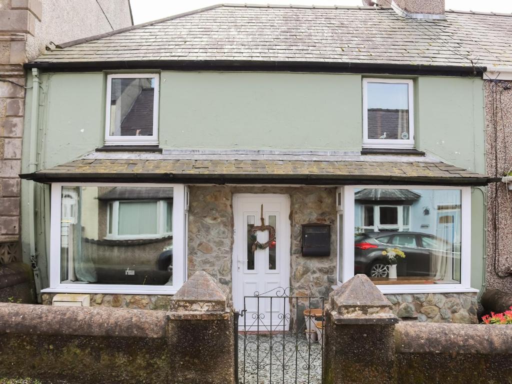 Casa pequeña con puerta blanca y ventanas en Chapel Street Cottage, en Amlwch