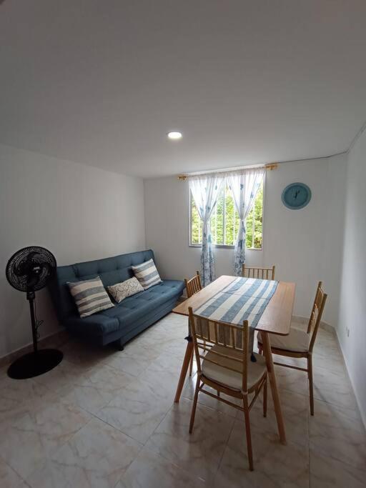 聖菲－安蒂奧基亞的住宿－Agradable y Económico Apartamento，客厅配有桌子和蓝色沙发