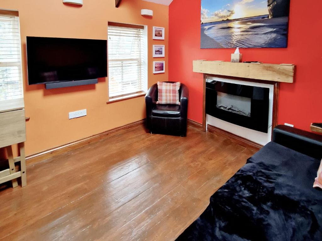 a living room with red walls and a fireplace at The Barn Annexe in St. Just